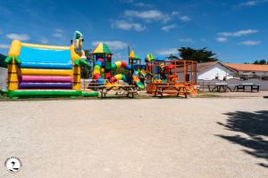 a playground with a bunch of colorful play equipment at Camping Les Violettes in La Faute-sur-Mer