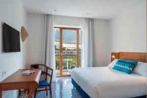 a hotel room with a bed and a desk and a window at Grand Hotel Flora in Sorrento