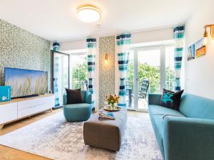 ein Wohnzimmer mit einem blauen Sofa und einem Fernseher in der Unterkunft FeWo Prora - PRORA week in Binz