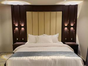 a large bed with a wooden headboard in a room at Makarim Al Nakheel serviced apartments in Rabigh