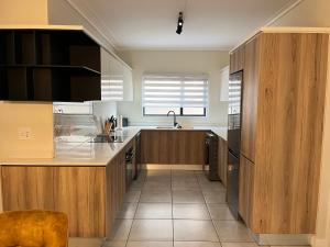 a kitchen with wooden cabinets and a sink at 17 Elizabeth Place - Beautiful and spacious self catering 3 bedroom unit next to Kyalami Racetrack with free WiFi - Perfect for a big family in Midrand Waterfall in Midrand