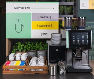 - une machine à café assise sur un comptoir à côté d'une table dans l'établissement Garner Hotel Augsburg Nord by IHG, à Augsbourg