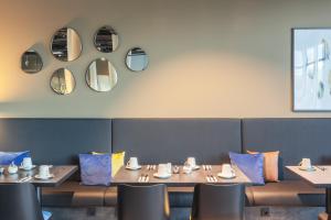 a dining room with wooden tables and chairs and mirrors at Garner Hotel Augsburg Nord by IHG in Augsburg