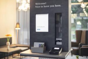 une pièce avec un mur portant une pancarte indiquant « Bienvenue, ravi de vous accueillir ici » dans l'établissement Garner Hotel Augsburg Nord by IHG, à Augsbourg