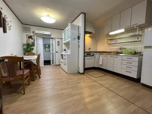 cocina con armarios blancos, mesa y comedor en 梅小路公園近辺の民宿, en Kioto