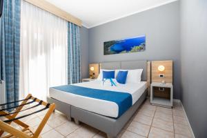 a bedroom with a bed with blue and white sheets at Bike&Boat Argentario Hotel in Porto Santo Stefano