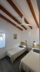 a bedroom with two beds and a ceiling fan at Apartamento con piscina y playa in Son Xoriguer +20 photos