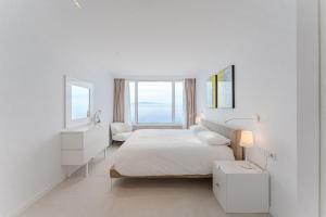 a white bedroom with a bed and two windows at SVB Aquasuites Luxury Penthouse - A02 in Santiago del Teide
