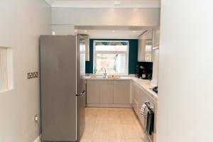 a kitchen with a refrigerator and a sink at New! Spacious 3Br Sleeps 6 With Free Parking, Wi-Fi and Netflix in Frimley