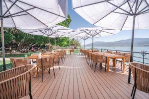a wooden deck with tables and chairs and umbrellas at Bungalow Cajititlan 2 bedrooms & lake view in Cajititlán