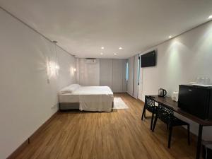 a bedroom with a bed and a desk and a television at Ziza Hospedagem in Maringá