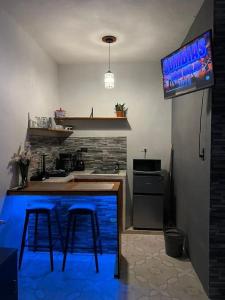 a kitchen with a bar with two stools and a television at Departamento PLAYA GRIS in Ciudad del Carmen