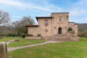 an old stone house with a grassy yard at The Stone House in Bárcena de Pie de Concha