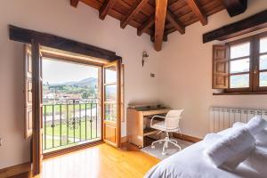 a bedroom with a bed and a desk and a window at The Stone House in Bárcena de Pie de Concha