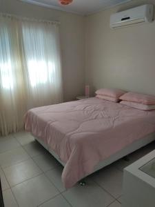 a bedroom with a large bed with pink sheets at Casa verão 2025 in Tramandaí +9 photos