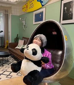 a little girl sitting in a chair holding a panda bear at Chengdu city center Tianfu Square Kuanzhai Alley People's Park subway post-modern design 85 square meters 2 bedrooms 1 living room design B&B HD cinema family suite in Chengdu
