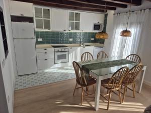 a kitchen with white cabinets and a table and chairs at Casa La tranca in Cuevas del Valle +18 photos