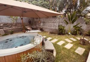 a hot tub in a yard with an umbrella at Le Ravenala Maison SPA 2 chambres 2 salles de bain in Saint-Denis