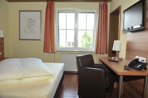a hotel room with a bed and a desk and a computer at Hotel Grüters in Mülheim-Kärlich