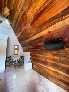 a living room with a wooden wall with a flat screen tv at Pousada Refúgio da Marola in São Lourenço do Sul