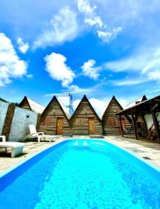 a swimming pool in front of some wooden buildings at Pousada Refúgio da Marola in São Lourenço do Sul