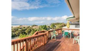 a balcony with a table and chairs and the ocean at Wine Downtime - Mangawhai Holiday Home in Mangawhai