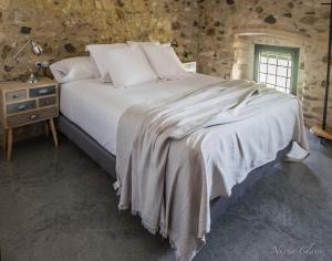a bed in a room with a stone wall at Can Serrà 1786 in Llagostera