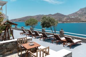 a patio with chairs and tables next to a body of water at Astrio Suites in Livadi