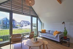 a living room with a couch and a large window at NIEUW! Vakantiehuis Singel 3A met SAUNA - baddomburg in Domburg