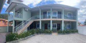 a large blue house with a balcony and stairs at Moradas da Bibi in Guarda do Embaú