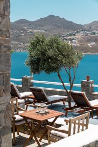 a group of tables and chairs with a view of the water at Astrio Suites in Livadi
