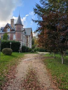 una casa con una strada sterrata davanti di Chambre d'hôte - petit château à la campagne a Saint-Aubin-Epinay