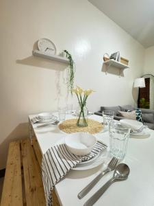 a dining room table with plates and silverware on it at Cozy Escape Calaca in Calaca