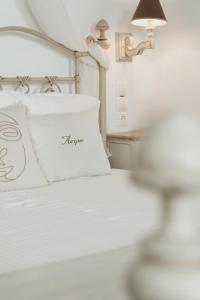 a white bed with a white pillow and a lamp at Astrio Suites in Livadi