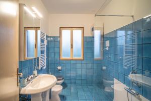a blue tiled bathroom with a sink and a toilet at La Casetta di Roveredo in Roveredo in Piano