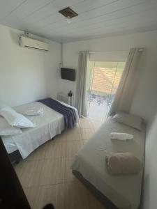 a hotel room with two beds and a window at Moradas da Bibi in Guarda do Embaú