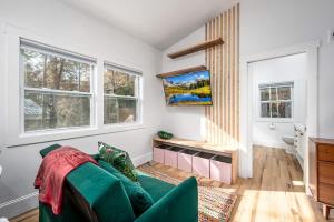 a living room with a green couch and windows at Two Tree Houses - Galaxy & Full Bloom in Pittsboro
