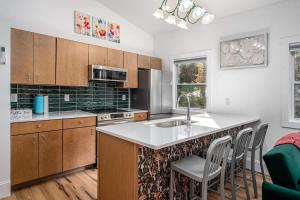 a kitchen with a sink and a counter with chairs at Two Tree Houses - Galaxy & Full Bloom in Pittsboro