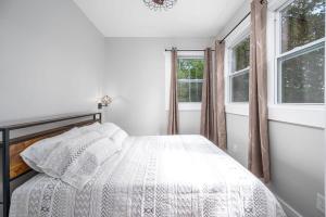 a bedroom with a bed and two windows at Elevate Tree House Community in Pittsboro