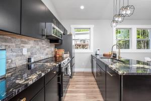 a kitchen with black cabinets and marble counter tops at Elevate Tree House Community in Pittsboro +70 photos