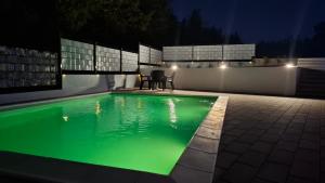 a swimming pool with green water at night at Vila Roda in Banja Luka