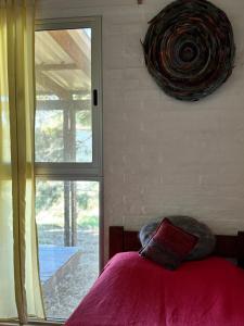 a bedroom with a bed with a pillow and a window at Monoambiente en Valizas in Barra de Valizas