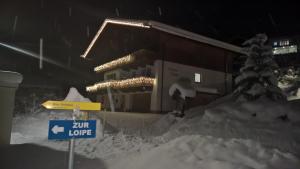 a building covered in snow at night with a sign at Appartementhaus Untere Tanne in Lermoos
