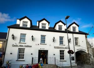 een wit gebouw met een zwart dak bij Sweeney's Hotel 2020 Limited in Dungloe