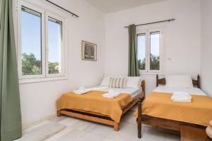 two beds in a room with two windows at Marathitis cottage house - Aegean sea view in Kanakis