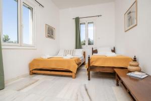 two beds in a room with two windows at Marathitis cottage house - Aegean sea view in Kanakis