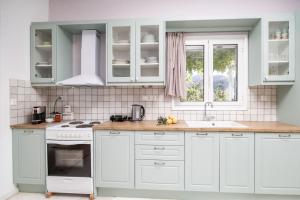a kitchen with white cabinets and a sink and a window at Marathitis cottage house - Aegean sea view in Kanakis +24 photos