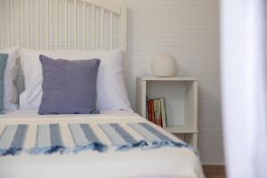 a bed with a blue pillow and a book shelf at Apiliotis sunrise beach villa in Ligaridia