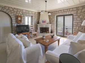 a living room with two white couches and a fireplace at Urania Luxury Villa Geofos in Póndi