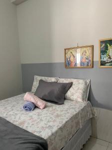 1 cama con 2 almohadas y 2 cuadros en la pared en Solange, en Vitória da Conquista